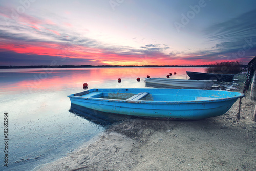 beautiful winter sunset at frozen lake with rustic blue boat