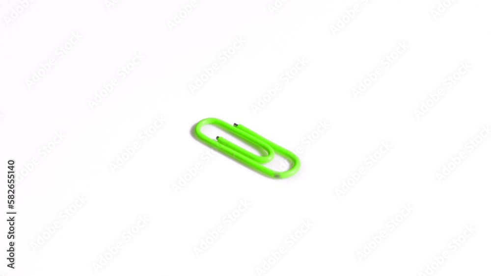 Green paper clip rotates on white background Green paper clip rotates on white background
