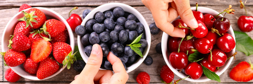 Fototapeta premium bowl of berries fruits and hands