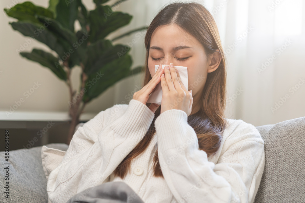 Sick, coronavirus or covid-19, attractive asian young woman, girl have a fever, flu and hand in use tissues paper sneezing nose, runny while sitting on sofa, couch at home. Health care on virus person Sick, coronavirus or covid-19, attractive asian young woman, girl have a fever, flu and hand in use tissues paper sneezing nose, runny while sitting on sofa, couch at home. Health care on virus person