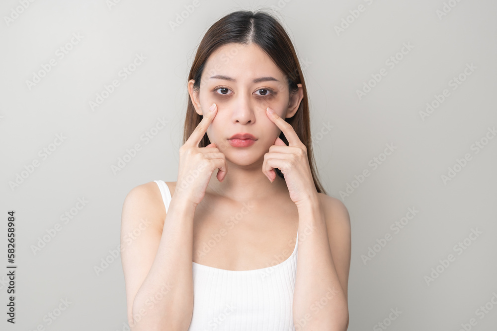 Bored, insomnia asian young woman, girl looking at camera, hand touching under eyes with problem of black circles or panda puffy, swollen and wrinkle on face. Sleepless, sleepy healthcare person. Bored, insomnia asian young woman, girl looking at camera, hand touching under eyes with problem of black circles or panda puffy, swollen and wrinkle on face. Sleepless, sleepy healthcare person.
