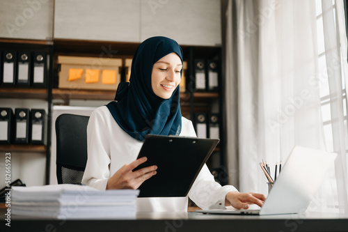 Young Arabic female entrepreneur wearing a hijab working online with a laptop at office