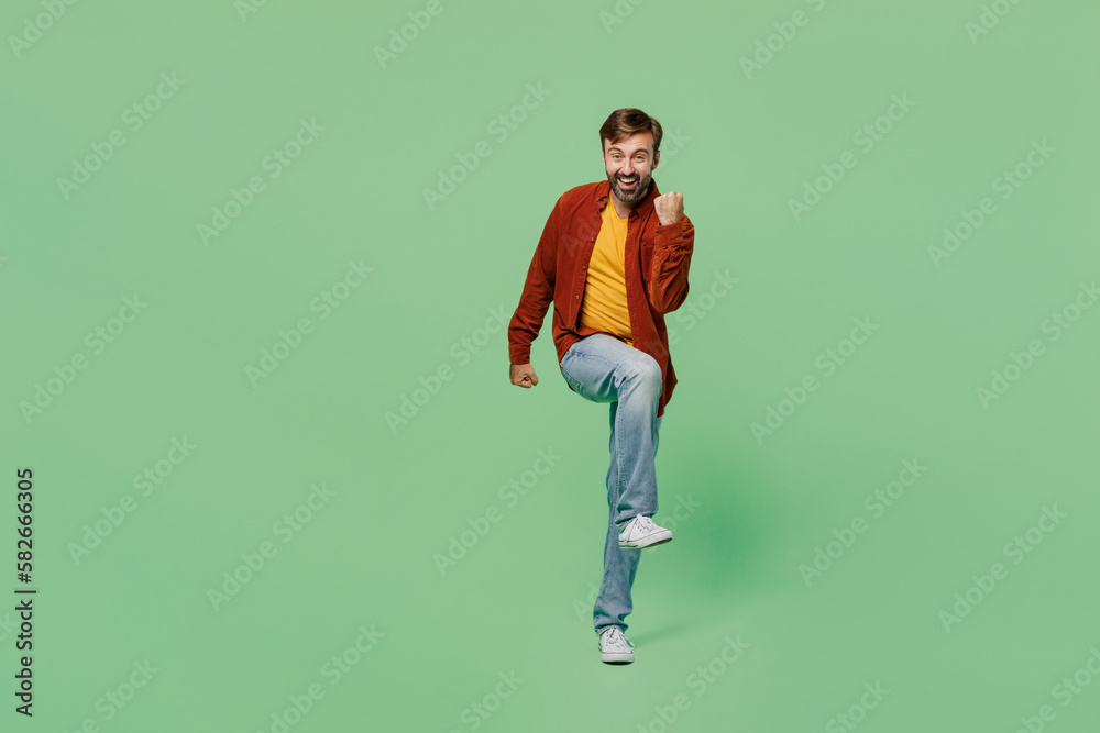 Full body fun elderly man 40s years old wears casual clothes red shirt t-shirt doing winner gesture celebrate clenching fists say yes isolated on plain pastel light green background studio portrait. Full body fun elderly man 40s years old wears casual clothes red shirt t-shirt doing winner gesture celebrate clenching fists say yes isolated on plain pastel light green background studio portrait.