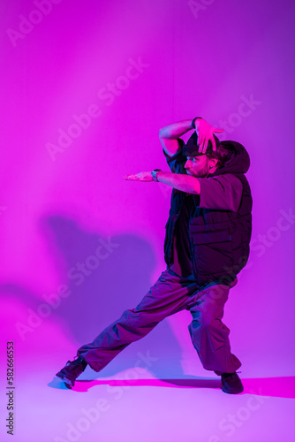 Handsome fashion professional man dancer in trendy fashionable clothes dancing in creative color studio with pink and neon light