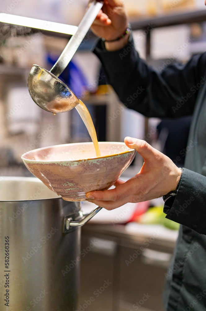 chef cooking tasty soup in big pot on restaurant kitchen chef cooking tasty soup in big pot on restaurant kitchen