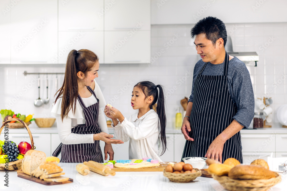 Portrait of enjoy happy love asian family father and mother with little asian girl daughter child play and having fun cooking food together with baking cookie and cake ingredient in kitchen