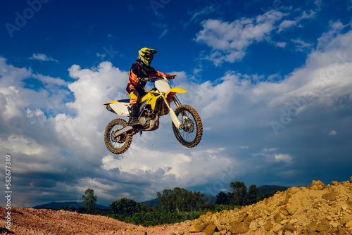 motocross rider jumping up the hill with a sky background