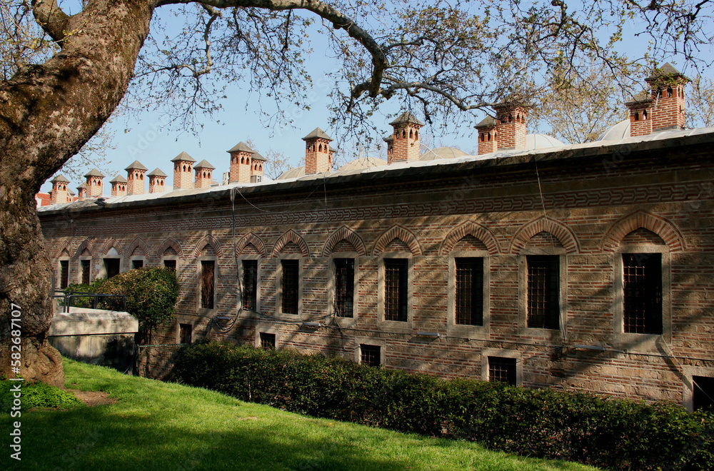 Obraz premium Side view of the exterior of the Koza Han building with multiple towers and a tree in the foreground in Bursa, Turkey