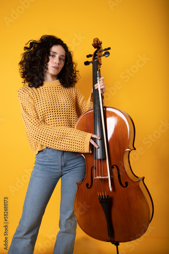 young girl with cello and casual clothing on yellow background