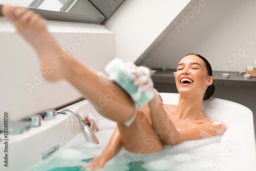 Lady Bathing Applying Shower Gel Via Sponge Washing Body Indoors
