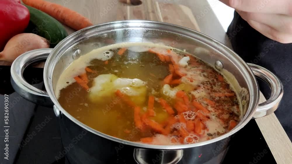 The process of making soup. Ingredients for cooking dinner in the home kitchen are placed in a saucepan. Woman's hands The process of making soup. Ingredients for cooking dinner in the home kitchen are placed in a saucepan. Woman's hands