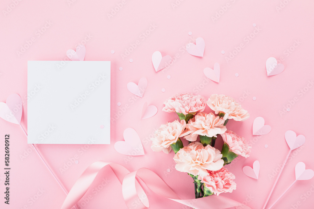Bouquet of beautiful pink carnation flowers, hearts and greeting card on pastel table for Happy mothers day. Flat lay. Bouquet of beautiful pink carnation flowers, hearts and greeting card on pastel table for Happy mothers day. Flat lay.
