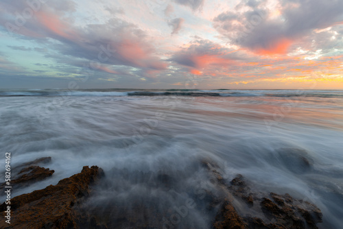 Wave water flowing around the rocks on the shore.