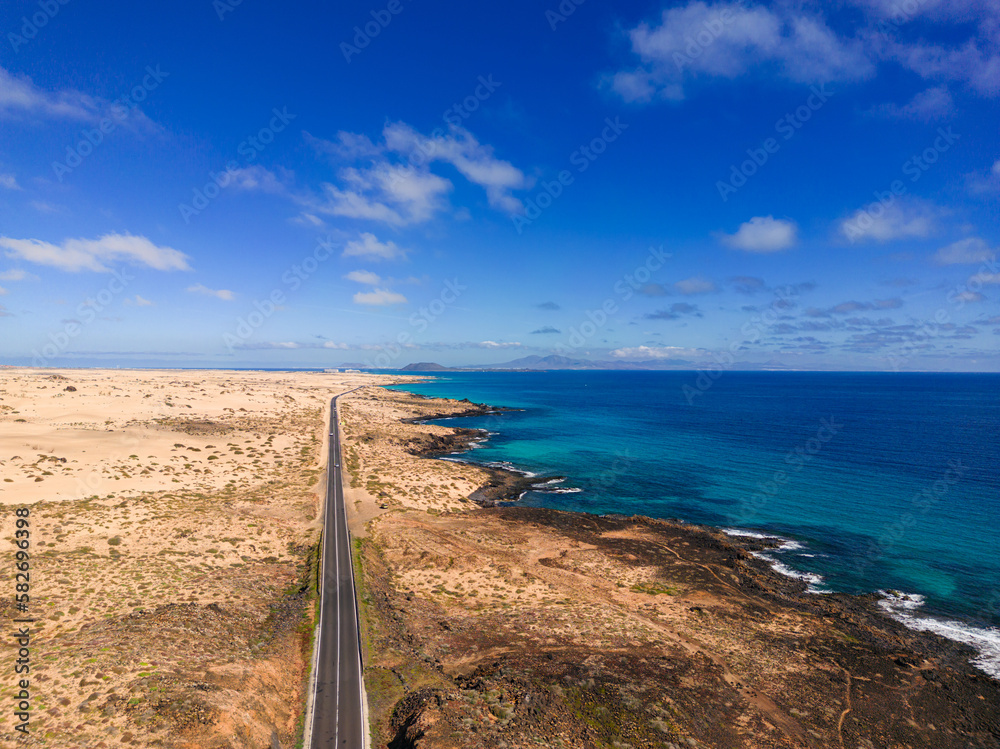 Aerial mid level panoramic view of the road between the coast and Parque Natural sand dunes heading to Corralejo Fuerteventura Spain