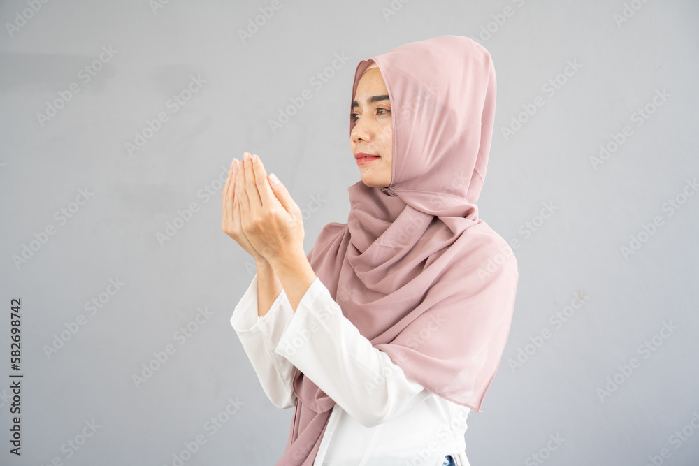 Muslim woman reading a book on gray background, in Islam study. Hand of muslim people praying with mosque interior background