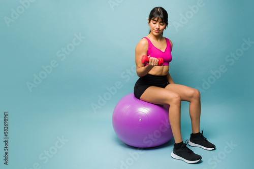 Hispanic sporty woman working out with a stability ball