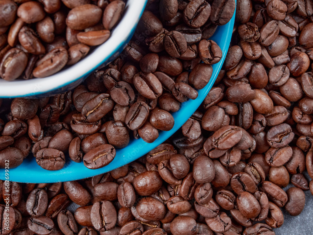 Obraz premium Cup of steaming hot coffee with coffee beans, coffee grinder, and coffee beans bag in background.