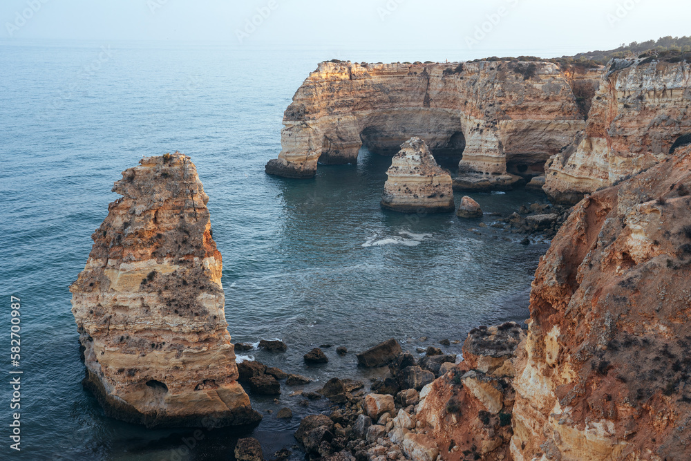 Obraz premium Cliffs, rock formations and natural arches in la Marina beach at sunset in the Algarve region near Albufeira and Portimao cities. Portugal.