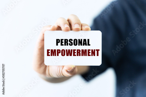 Personal empowerment text on blank business card being held by a woman's hand with blurred background. Business concept about personal empowerment.