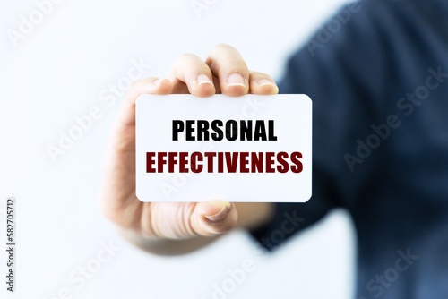 Personal effectiveness text on blank business card being held by a woman's hand with blurred background. Business concept about personal effectiveness.