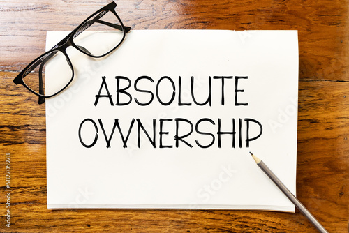 Εκτύπωση καμβά Absolute ownership text on blank notebook paper on wooden table with pencil and glasses aside