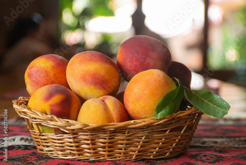 Fototapeta Naklejka Na Ścianę i Meble -  Ripe peaches fruits with leaves in basket on rustic background