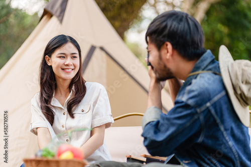 Asian man takes picture of girlfriend..Happy Asian couple taking photo by camera in camping outdoors in nature.