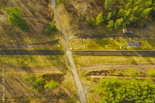 Rozległa równina porośnięta sosnowym lasem. Pomiędzy drzewami widać pojedyńczy, prosty tor kolejowy. Zdjęcie wykonano z wysokości przy użyciu drona.