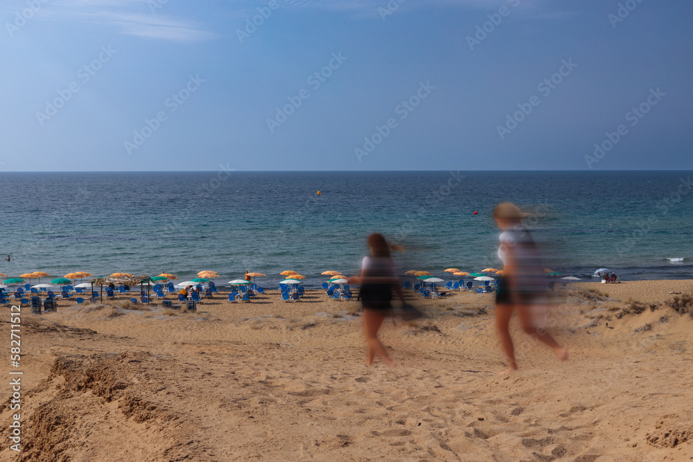 Tourists walking on the beach captured in motion, sandy beach on the island of Corfu.