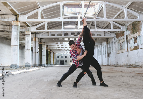 Boy and girl dancing hip-hop in old industrial building. Young couple training dance positions. Street urban lifestyle.
