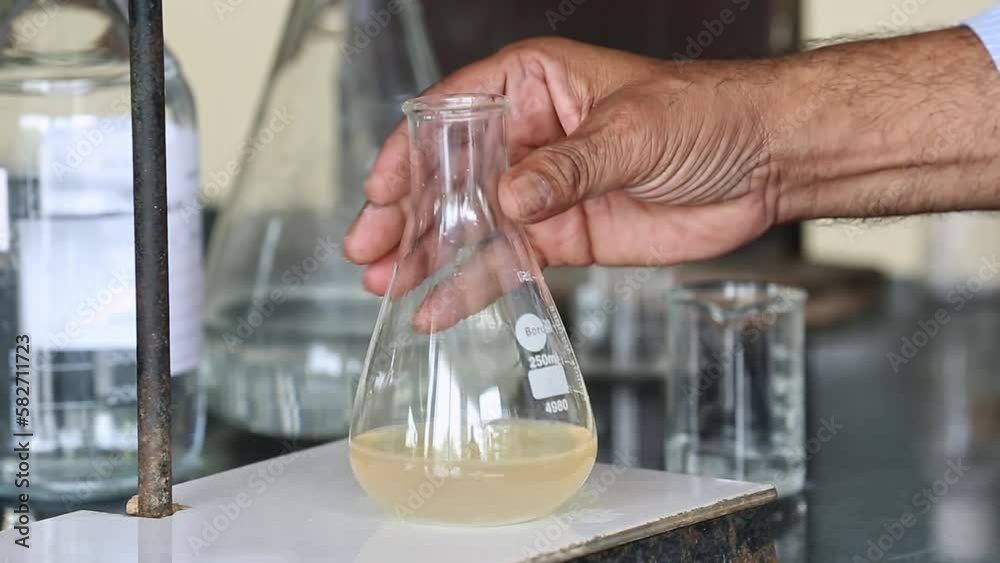 A closeup of checking the quality of soap in a conical flask by process A closeup of checking the quality of soap in a conical flask by process