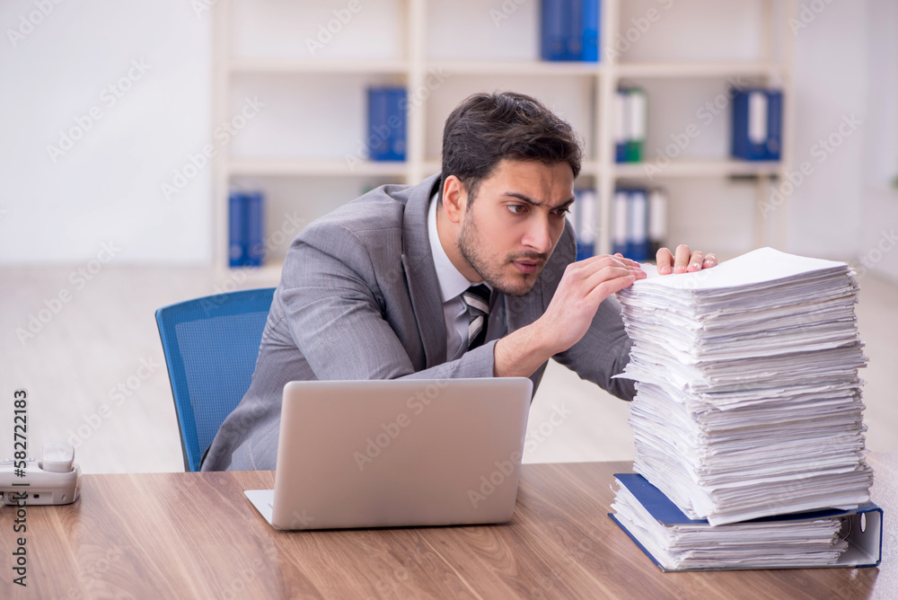Young male employee and too much work in the office Young male employee and too much work in the office