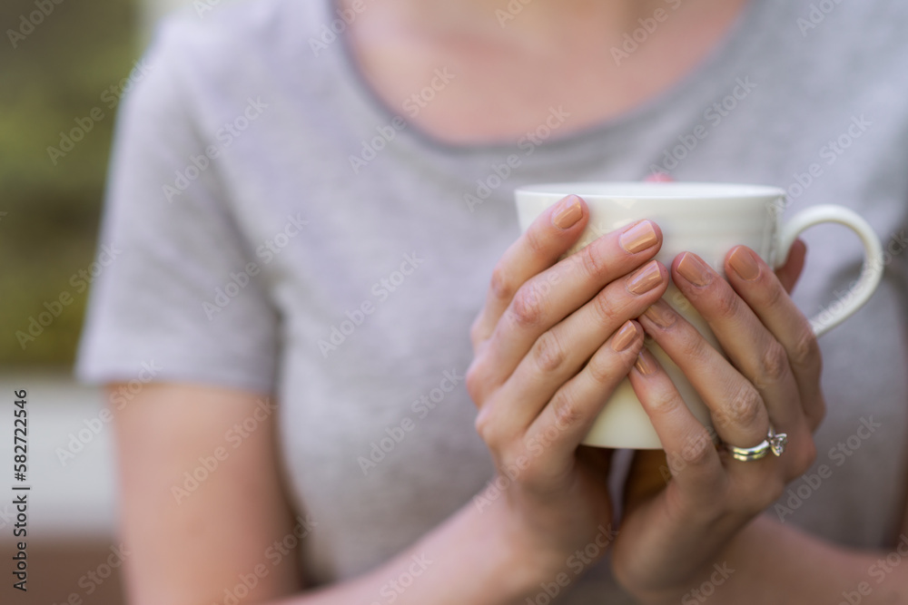woman holding cup of tea in her hands woman holding cup of tea in her hands
