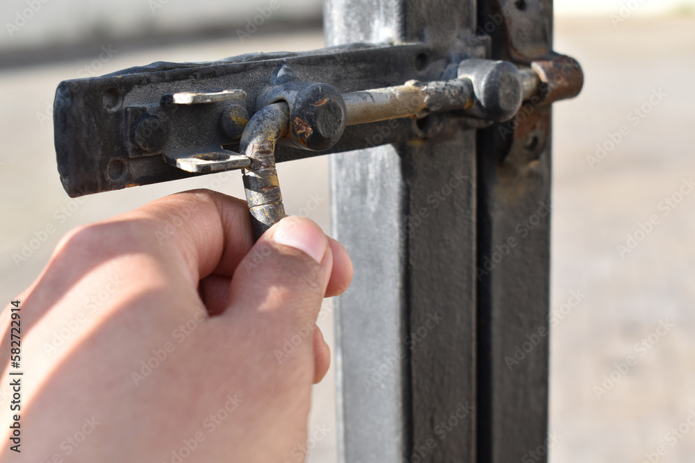 Human hand bolting a gate. Steel sliding bolt lock on the gate. Selective focus. Copy space. Human hand bolting a gate. Steel sliding bolt lock on the gate. Selective focus. Copy space.