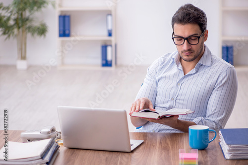 Young male employee reading book in the office