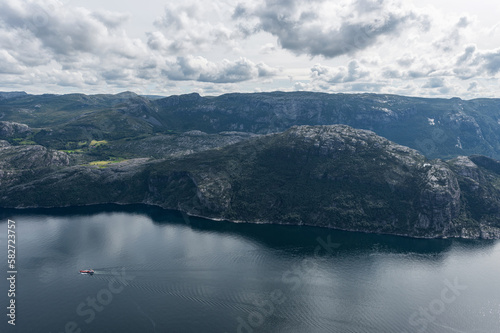 Norway Landscape. Preikestolen. River and Tourist Ferry in Background. Mountain. Blue sky.