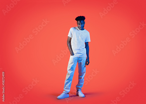 Carefree cool black guy in white posing on red