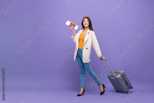 Fotografie Beautiful young Asian tourist woman walking with trolley suitcase, passport and