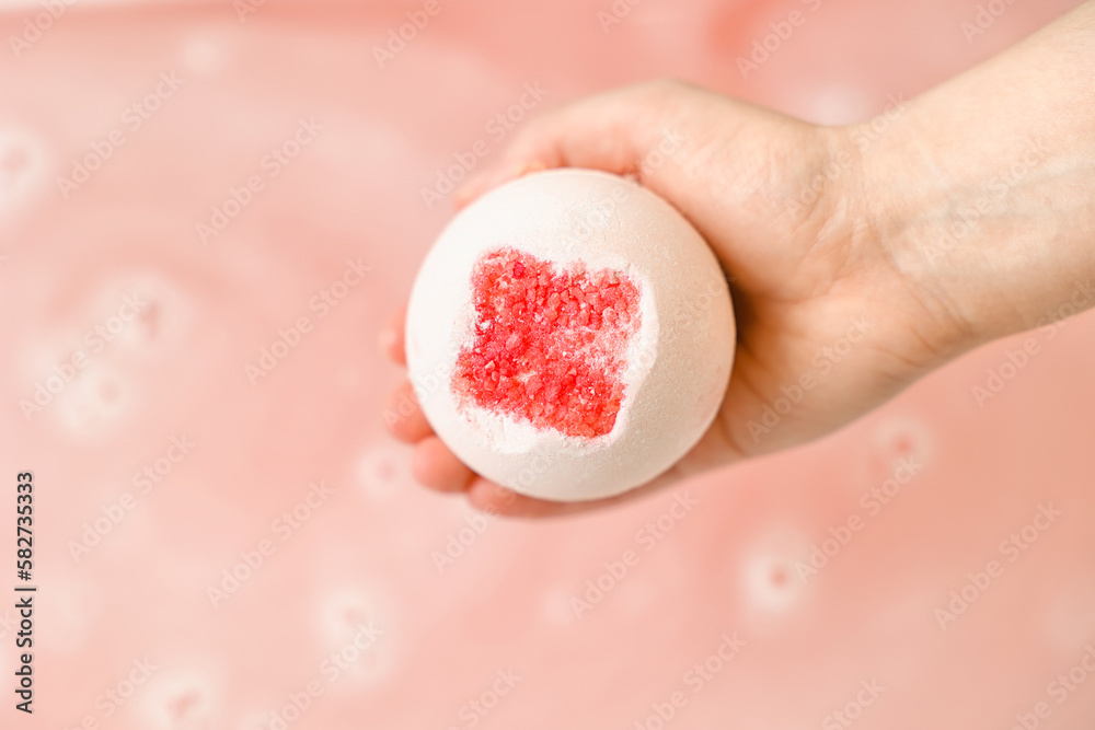 Fototapeta premium Woman with bath bomb above water in room, closeup