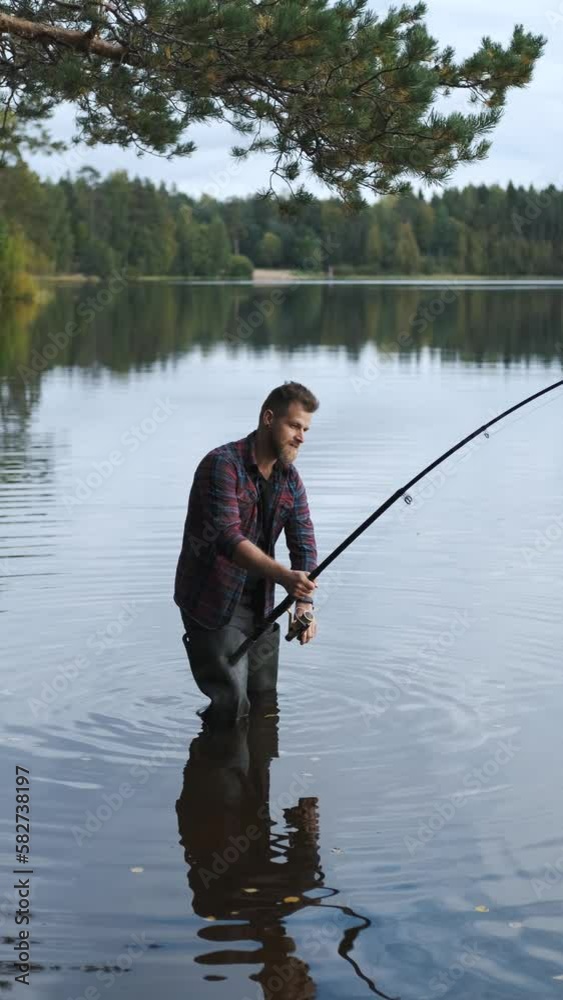 portrait of a man fishing standing in the lake, vertical video portrait of a man fishing standing in the lake, vertical video