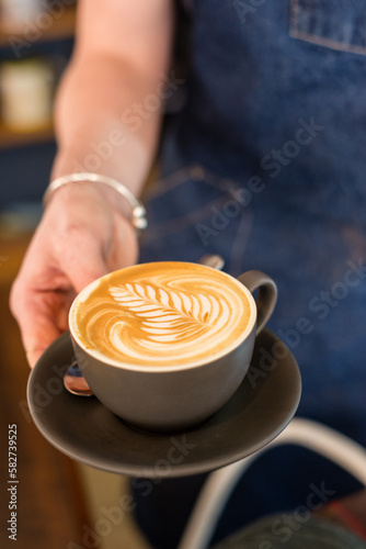 waitress holding flat white with pretty coffee art rosetta photo