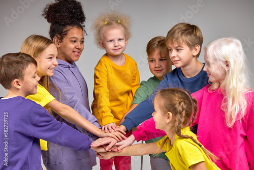 Teamwok And Children Concept. Diverse happy group of kids putting hands together, having fun, studying or playing game