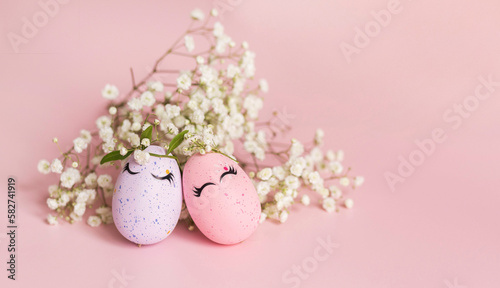 Stylish Easter pink and liliac eggs with cute faces in floral wreath crowns pink background. Happy Easter concept. Copy space. Isolated.