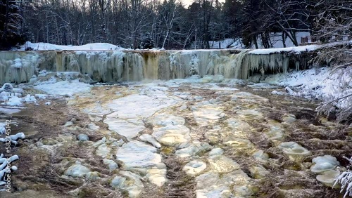 Golden water flows from a frozen winter waterfall. Keila Joa, Estonia. photo