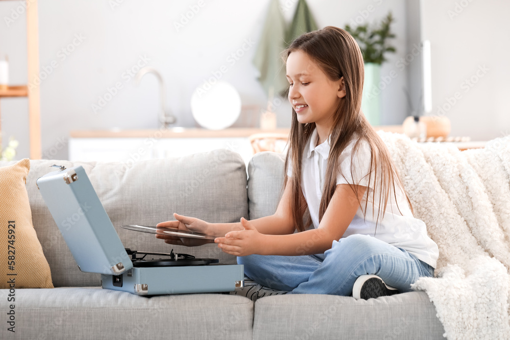 Little girl with record player sitting on sofa at home Little girl with record player sitting on sofa at home