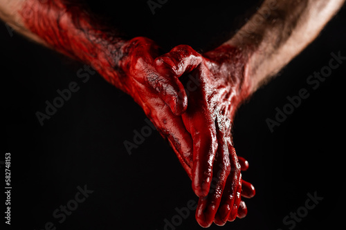Men's palms are stained with blood on a black background.