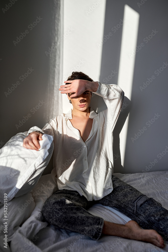 Fototapeta premium young pleasant brunette guy closing his ace with palm, man doesn't like morning, sunny day