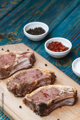 Fresh pork with ingredients for cooking on blue background