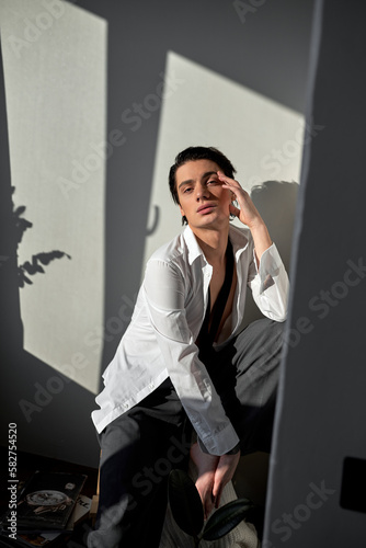 romantic sensual guy looking at camera, close up portrait. homosexual person with palm, hand on his cheeck photo