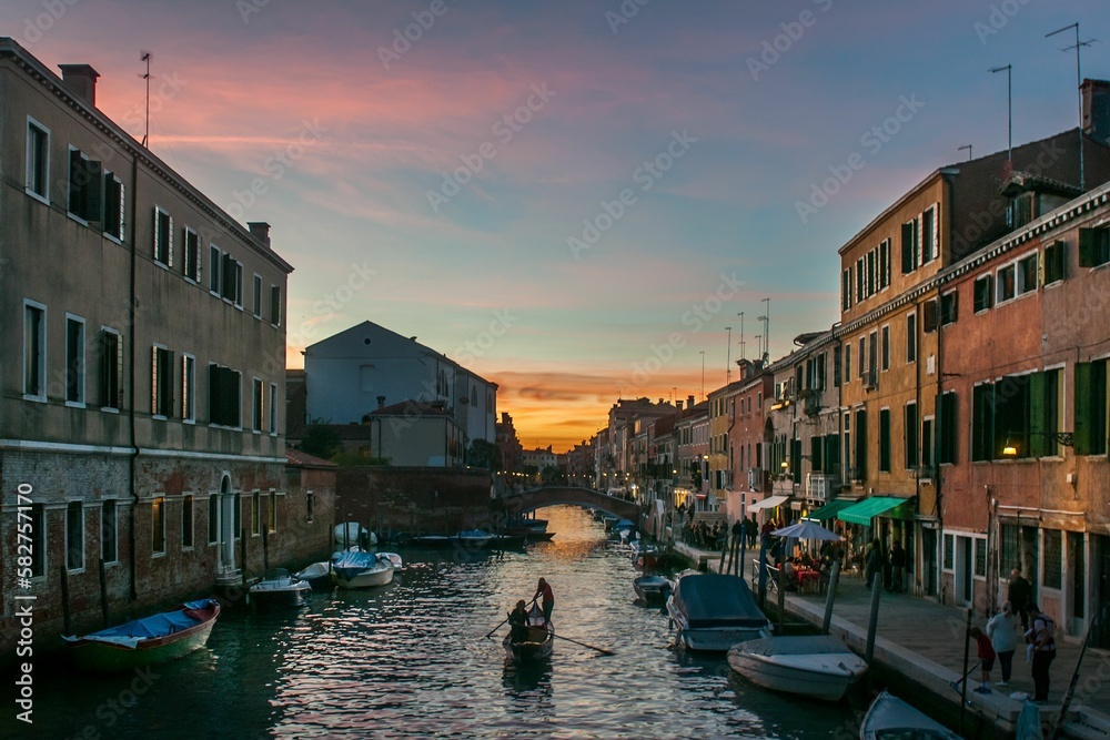 Aerial view of canal surrounded by buildings in Venice during sunset